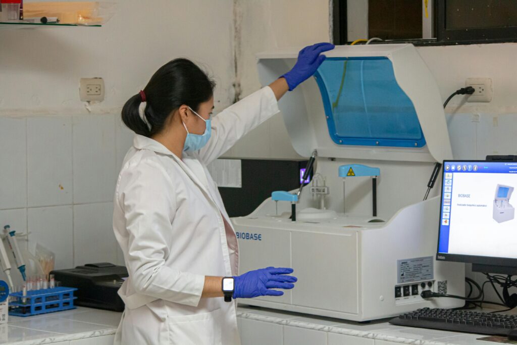 Woman scientist in lab coat working with laboratory equipment indoors.